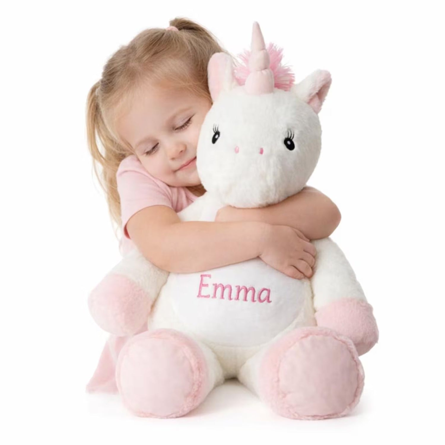 Child hugging a plush unicorn toy with 'Emma' embroidered on it against a white background