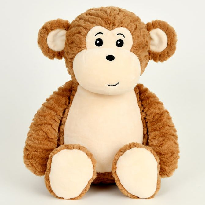 A plush toy monkey sitting upright against a plain light gray background. The monkey has medium brown textured fur on its head, arms, and legs, with a cream-colored face, inner ears, and feet, and simple black embroidered facial features.