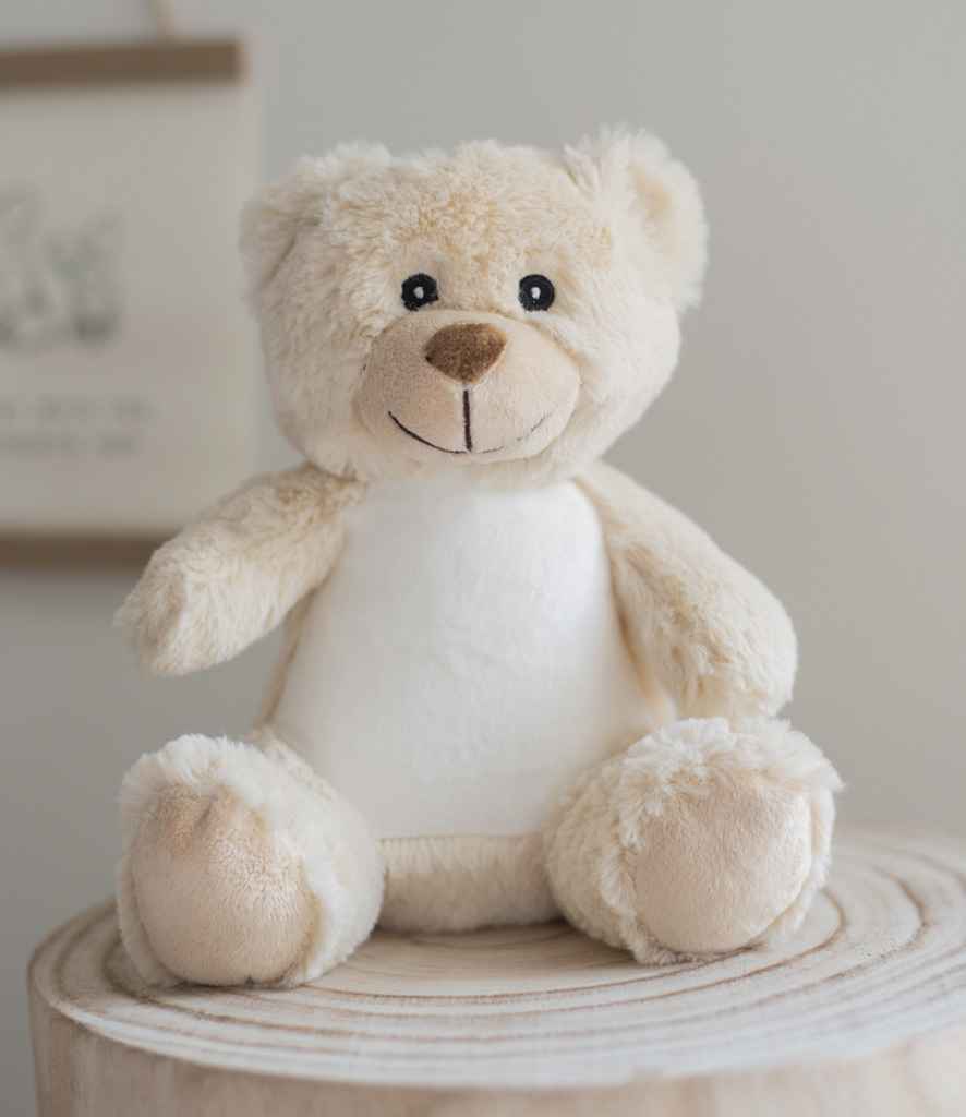 Cute teddy bear sitting on a wooden surface with a neutral background