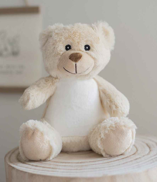 Cute teddy bear sitting on a wooden surface with a neutral background