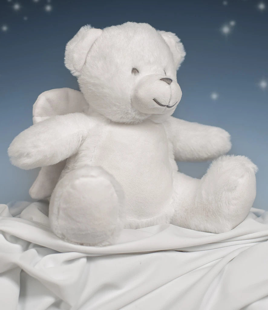 White teddy bear sitting on a white blanket with a blue starry night background