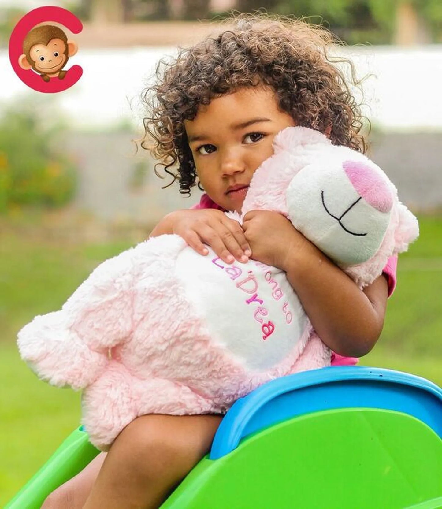 Child holding a pink stuffed animal outdoors