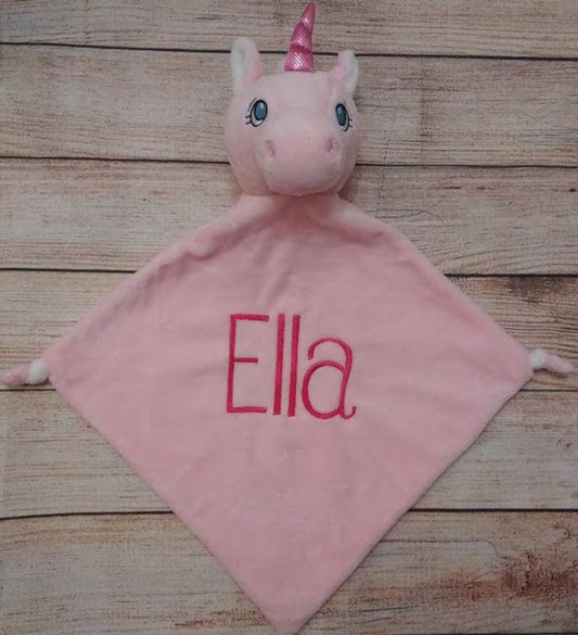 Pink unicorn plush toy with 'Ella' embroidered on a wooden surface