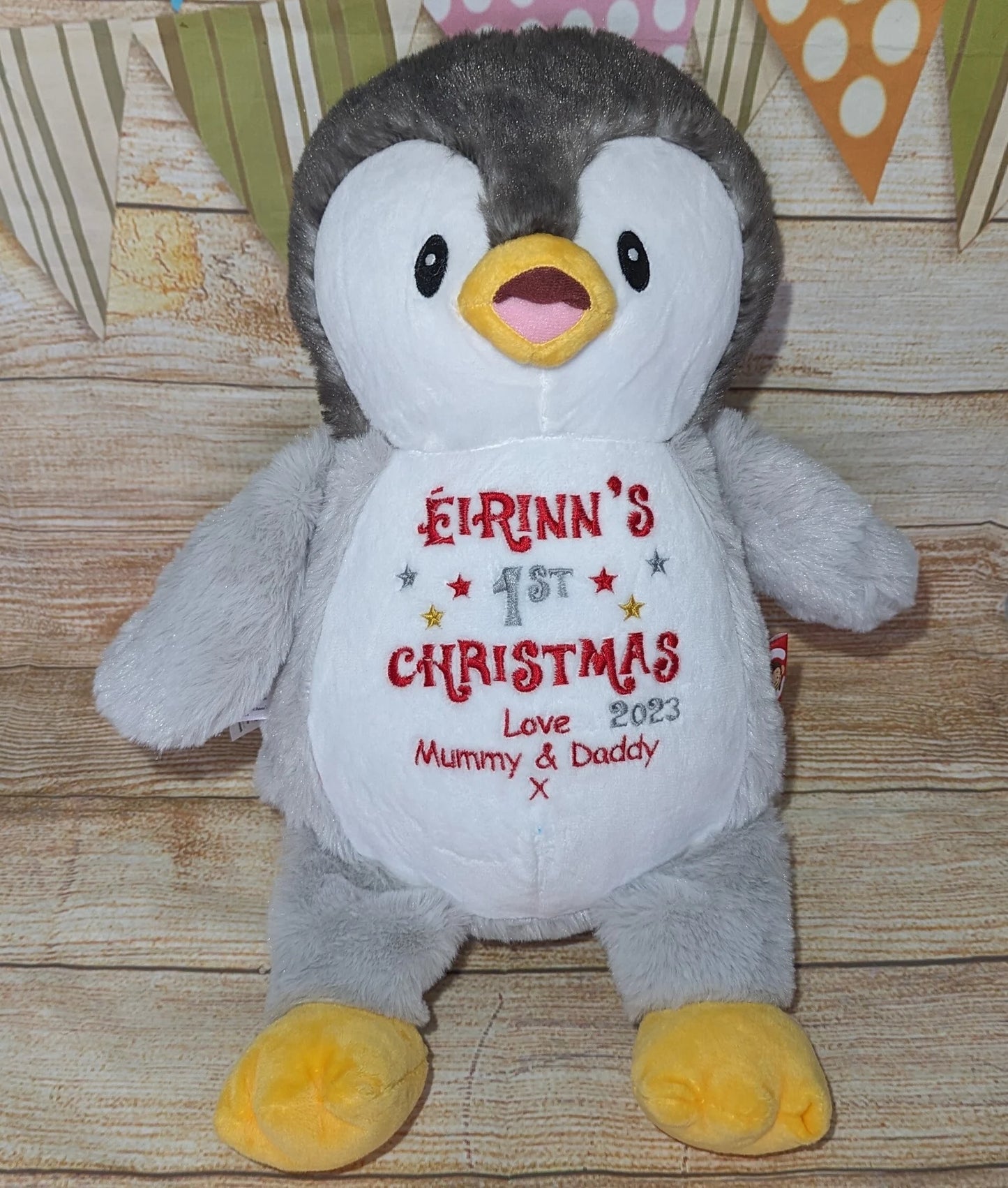 Plush penguin toy with personalized text on a wooden surface