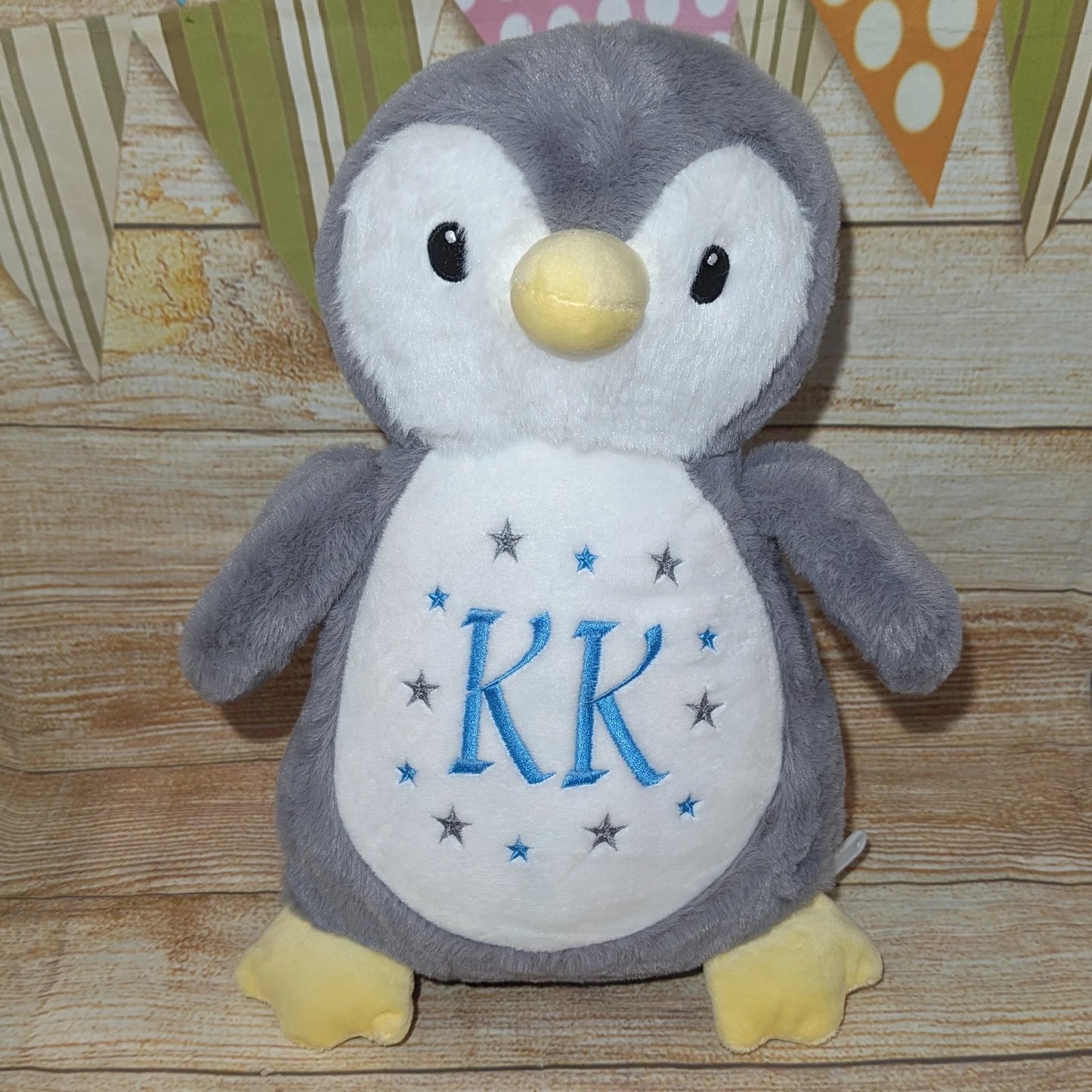 Plush penguin toy with 'KR' on a wooden surface