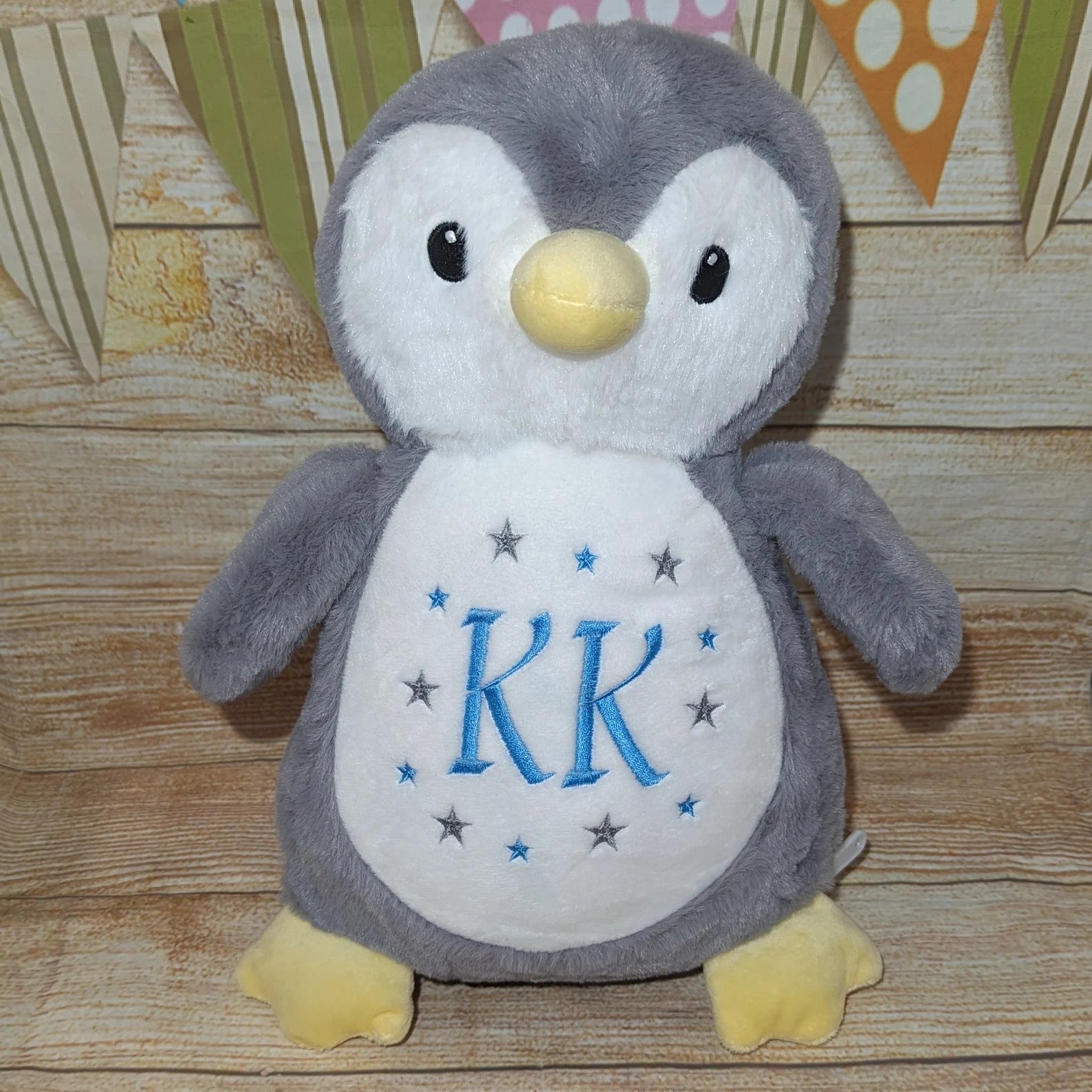 Plush penguin toy with 'KR' on a wooden surface