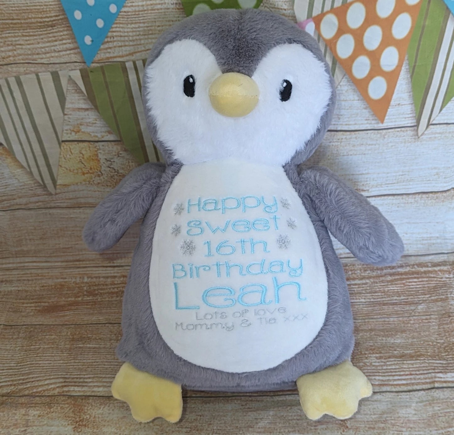 Plush penguin toy with personalized message on a wooden surface