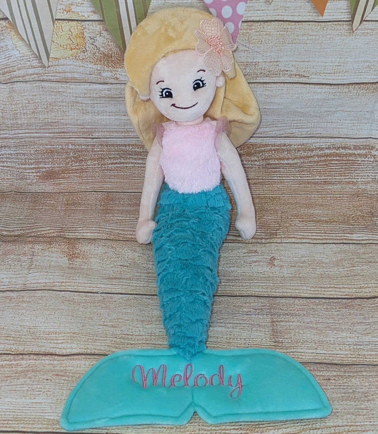 Mermaid doll with blonde hair and blue tail on a wooden surface