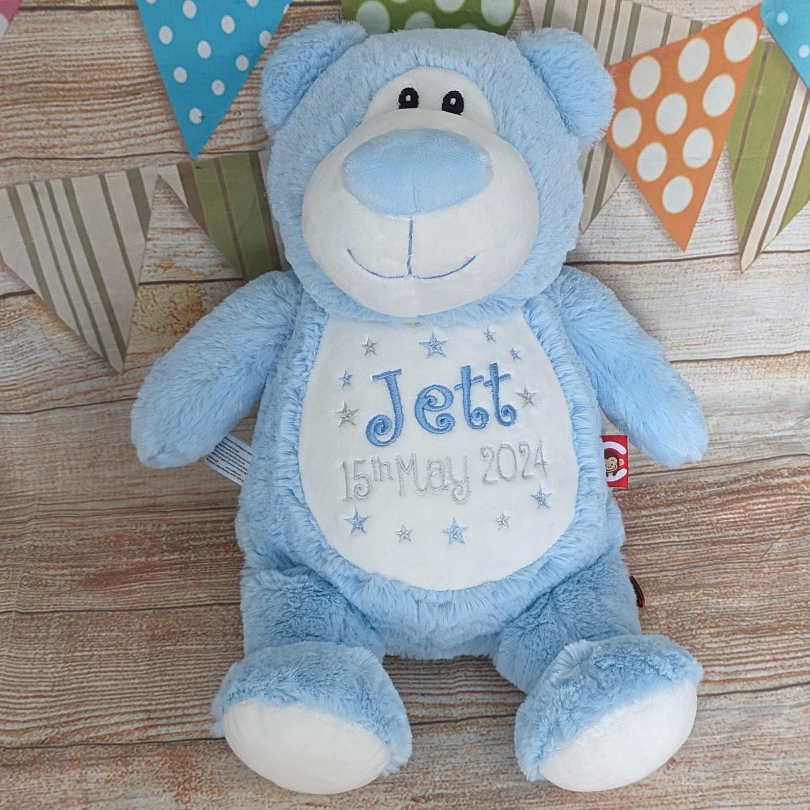 Blue teddy bear with personalized text on a wooden surface