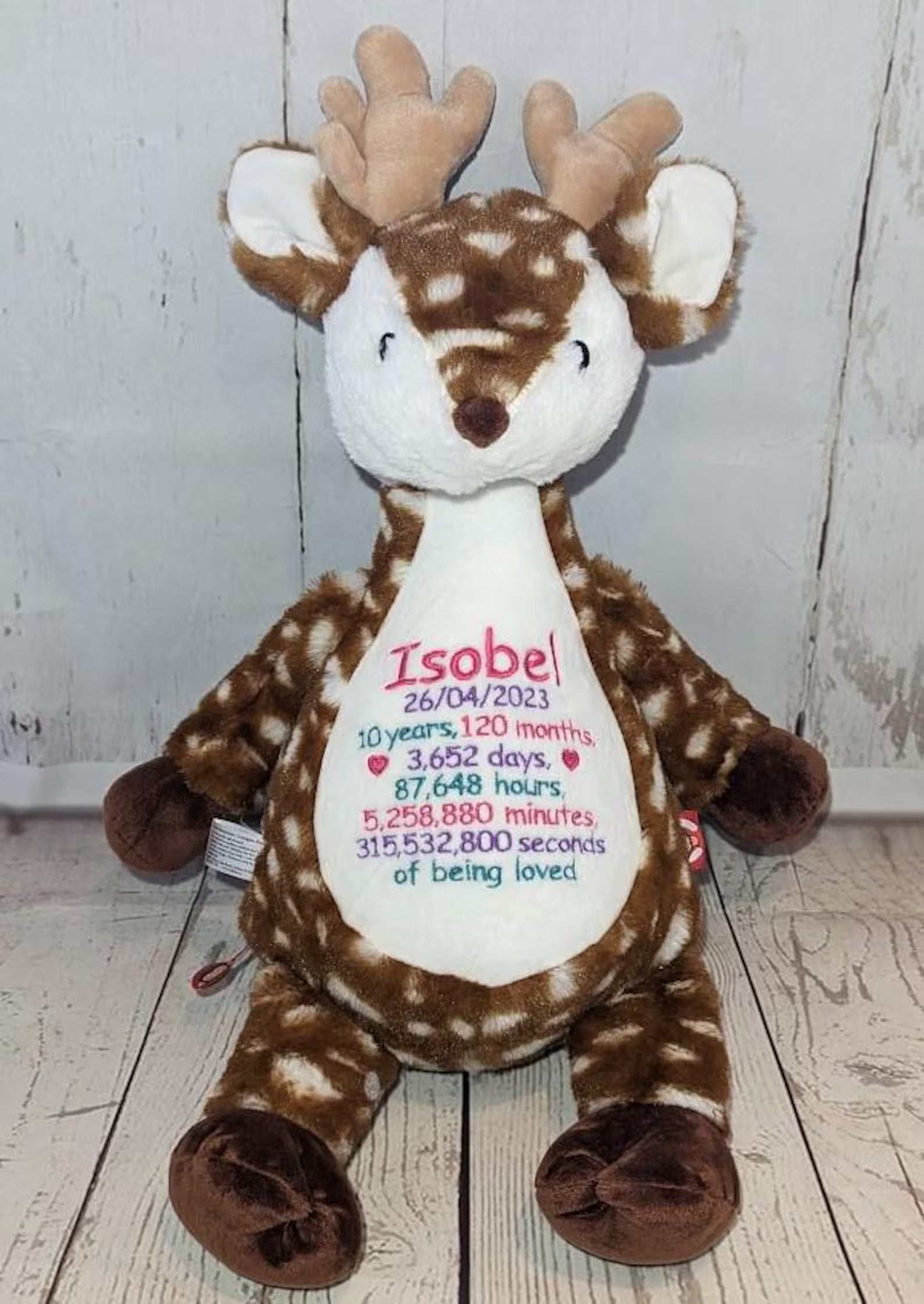 Stuffed reindeer toy with personalized text on a wooden floor