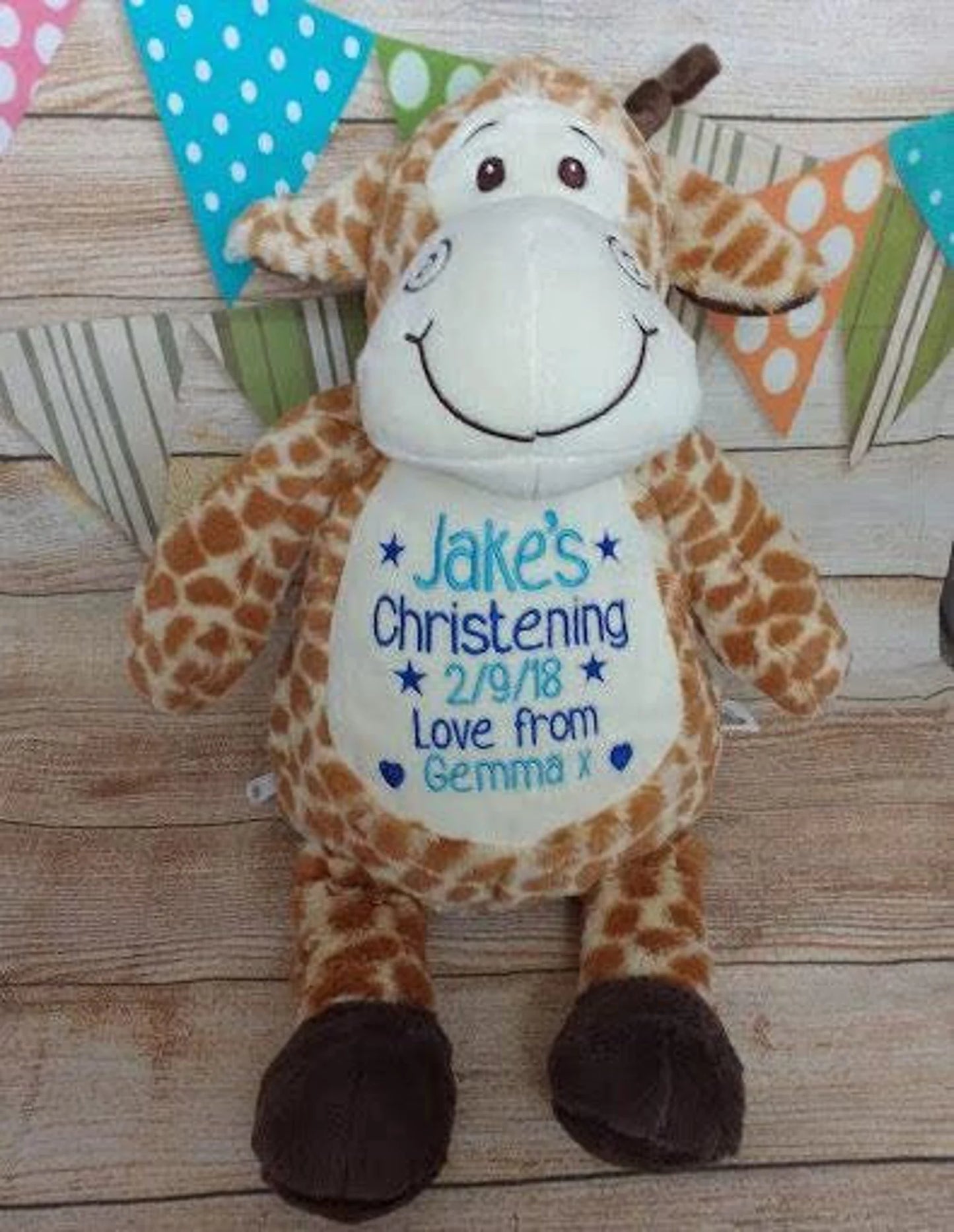 Giraffe plush toy with personalized text on a wooden surface with party decorations.