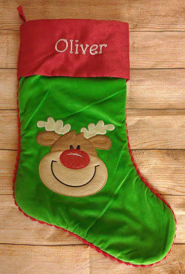 Green Christmas stocking with a reindeer face and red top on a wooden surface
