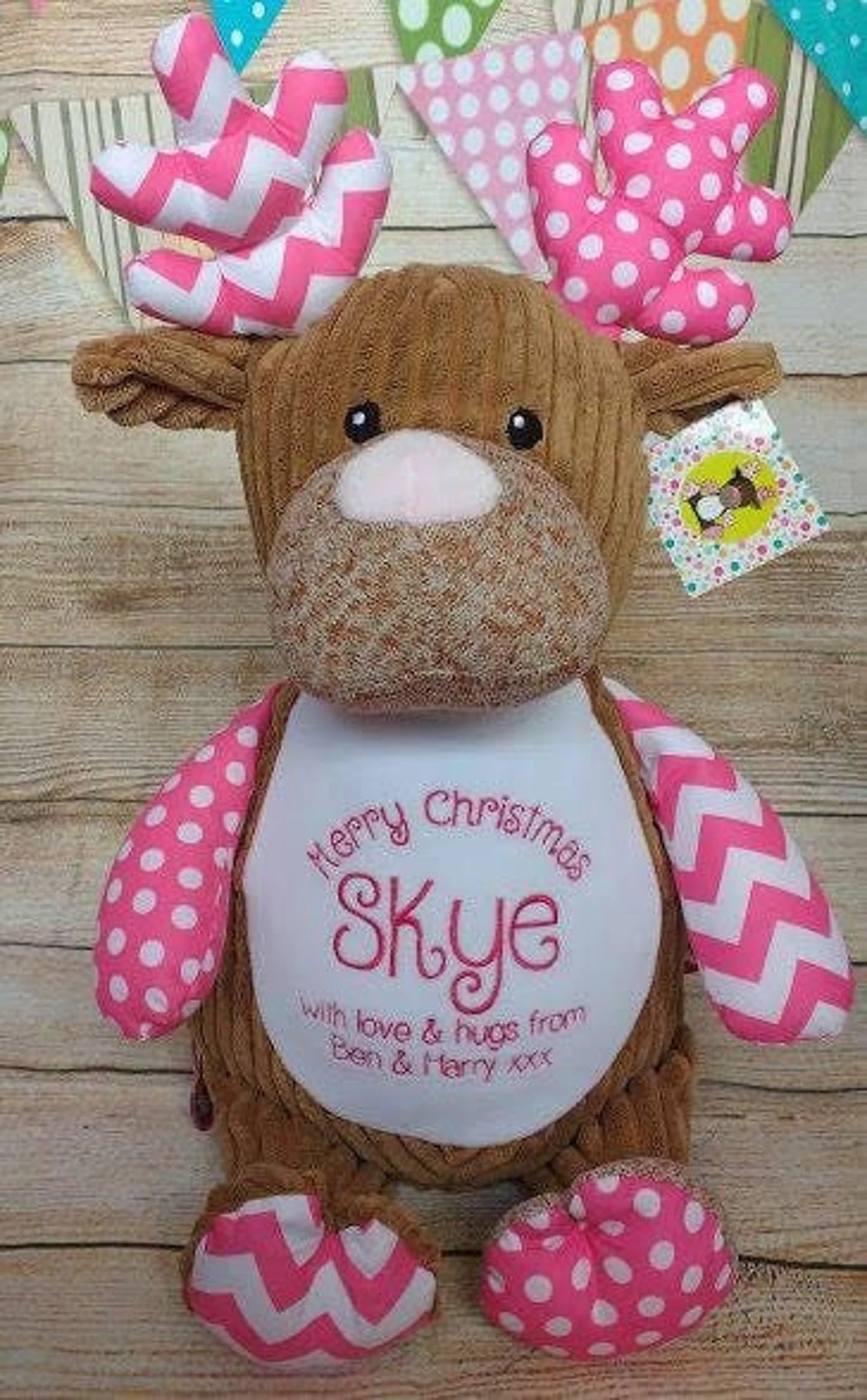 Plush reindeer toy with pink and white decorations on a white background