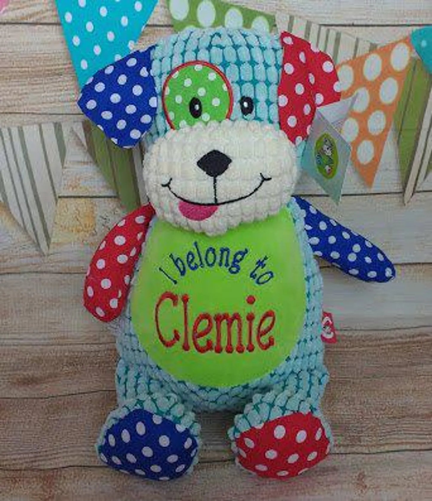 Colorful teddy bear with a name tag on a wooden background