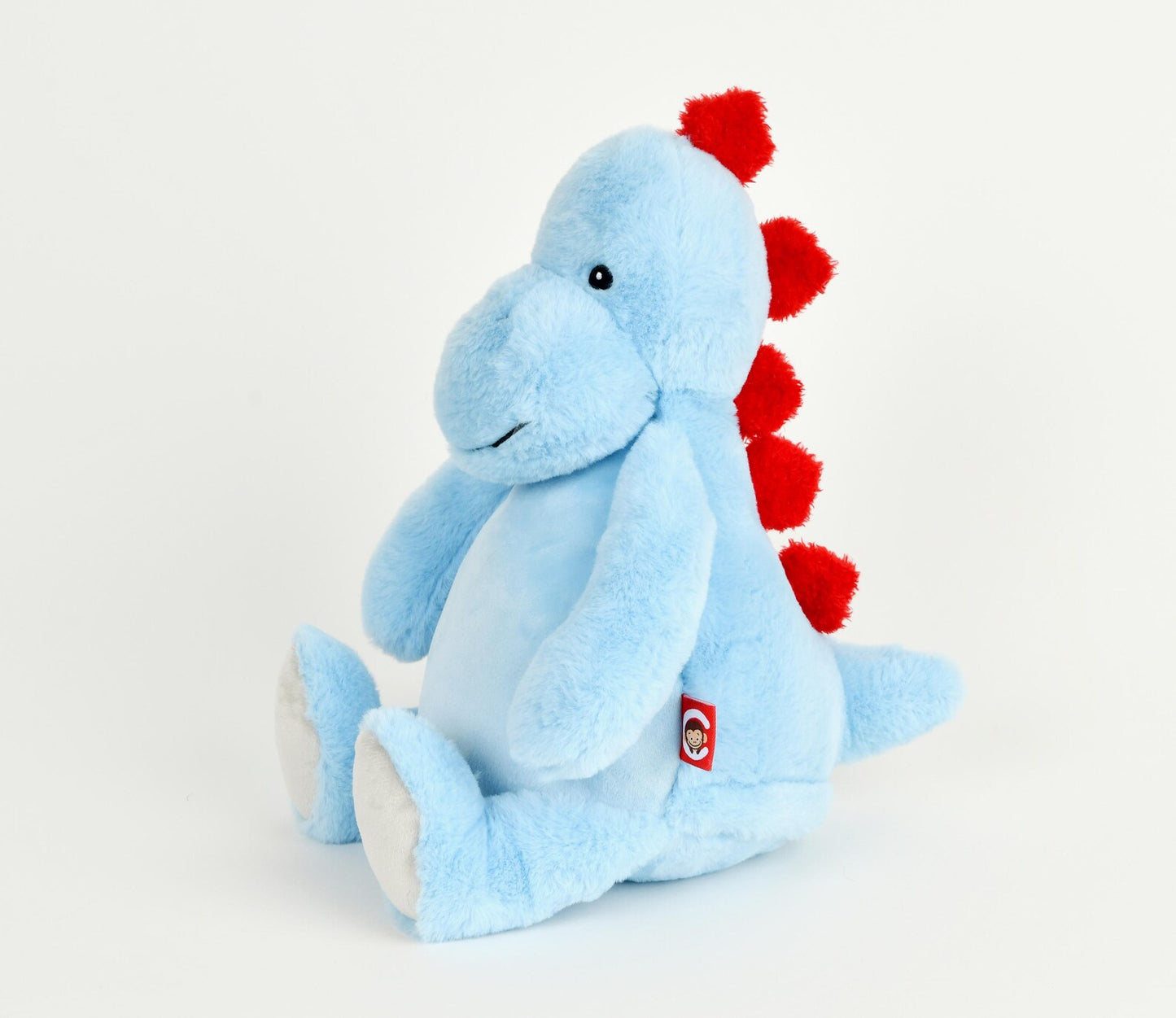 Blue plush dinosaur toy with red spikes on a light gray background