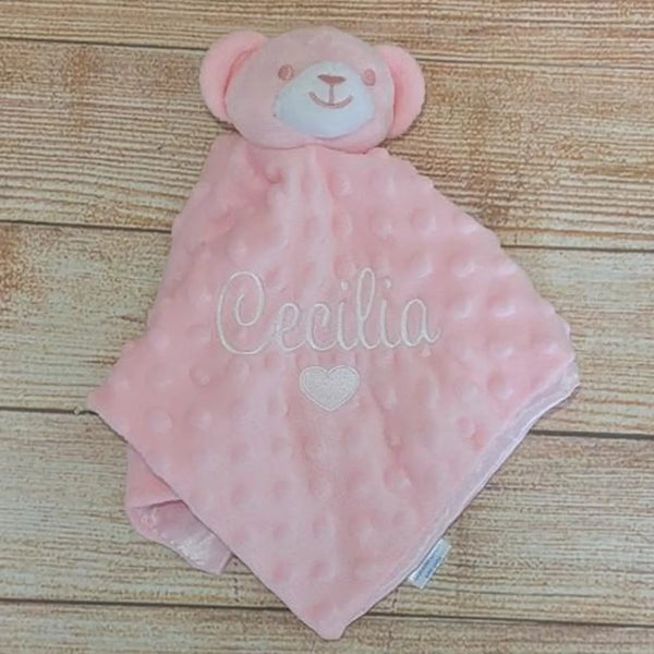 Pink teddy bear security blanket with 'Cecilia' embroidered on a wooden surface