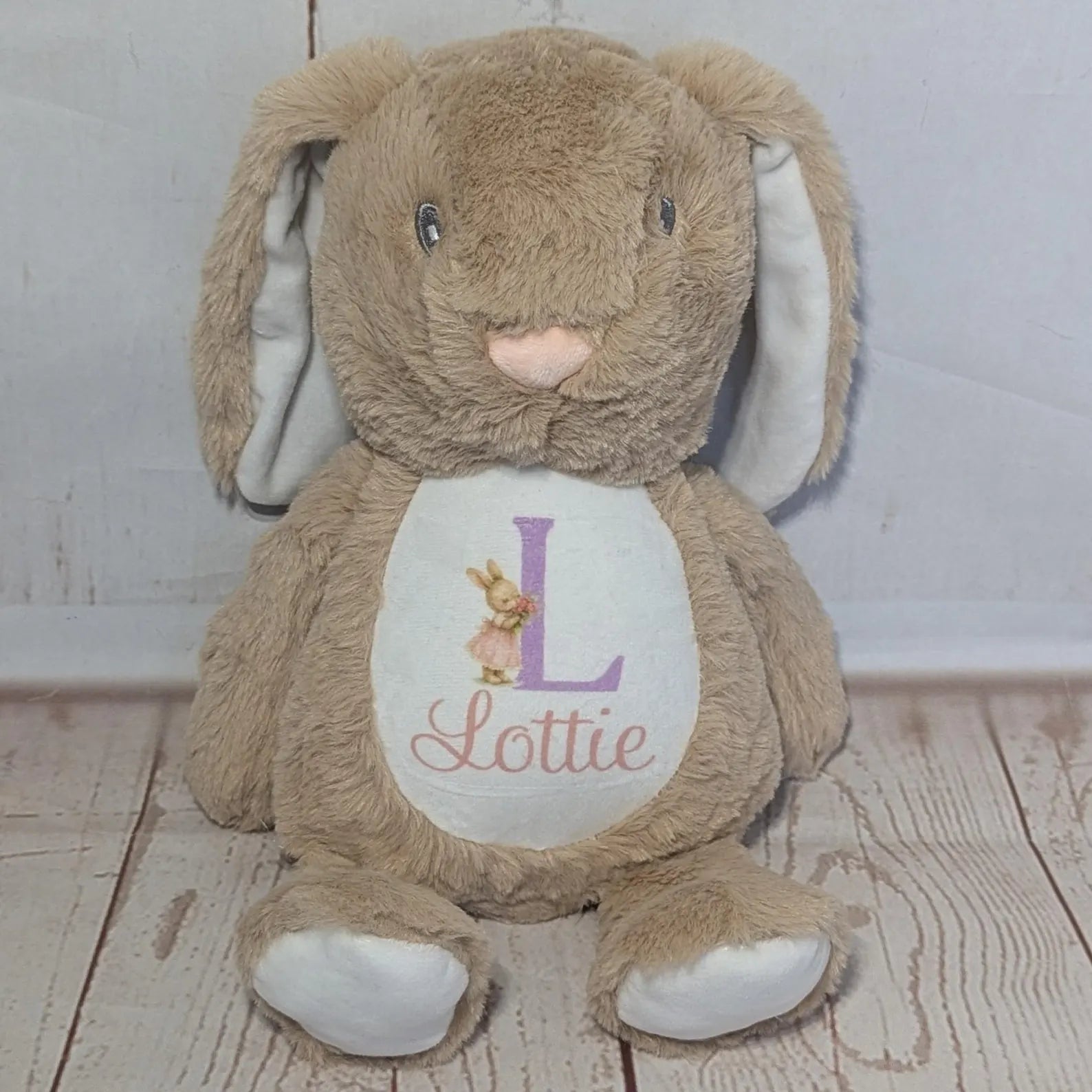 Plush bunny toy with a name tag on a wooden floor