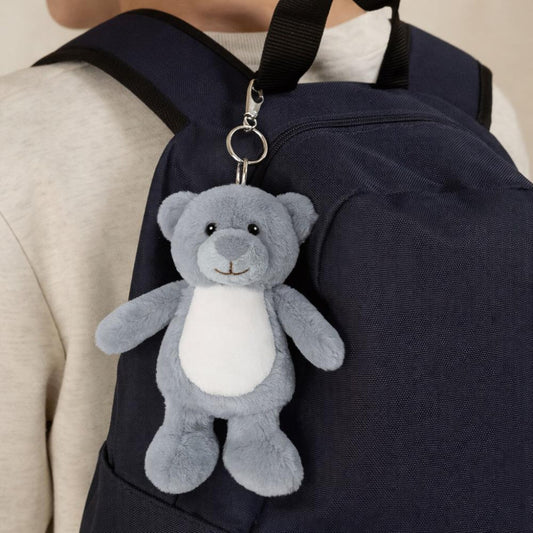 Gray teddy bear keychain attached to a navy backpack