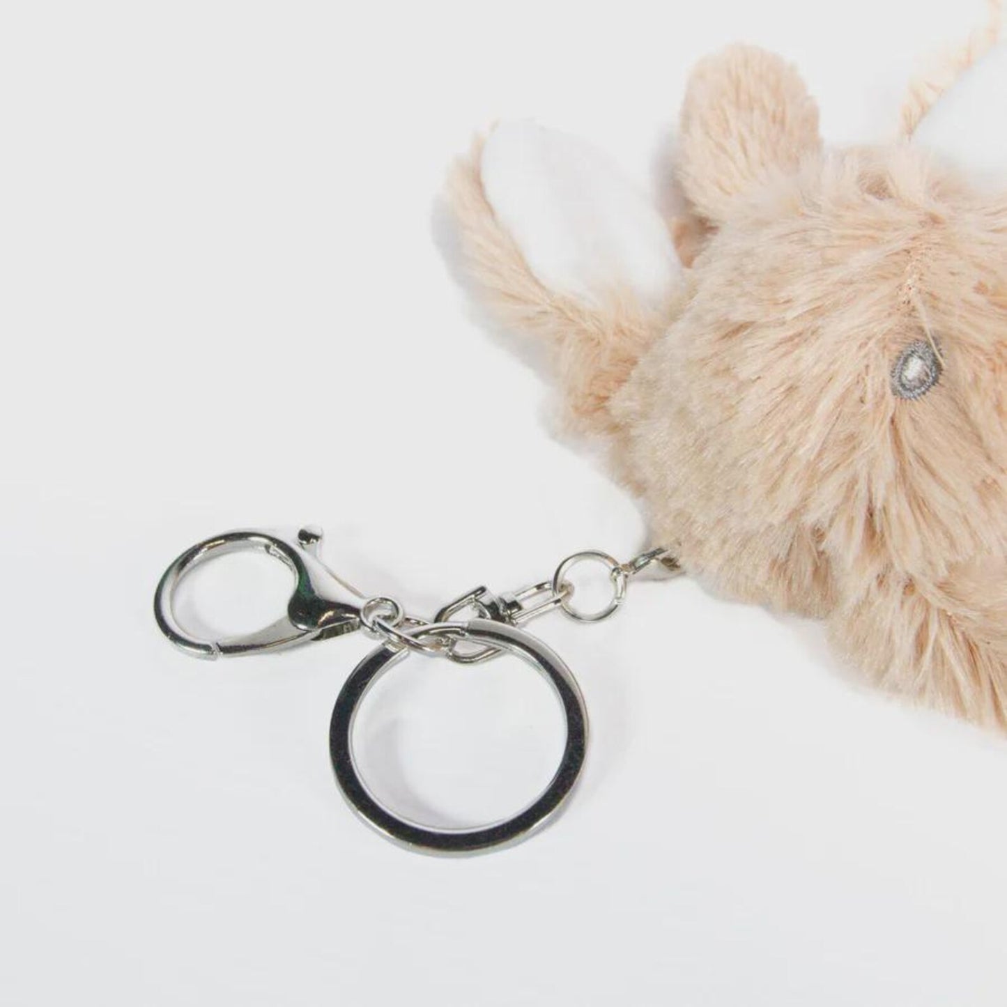 Metallic keychain with a fluffy beige toy on a white background