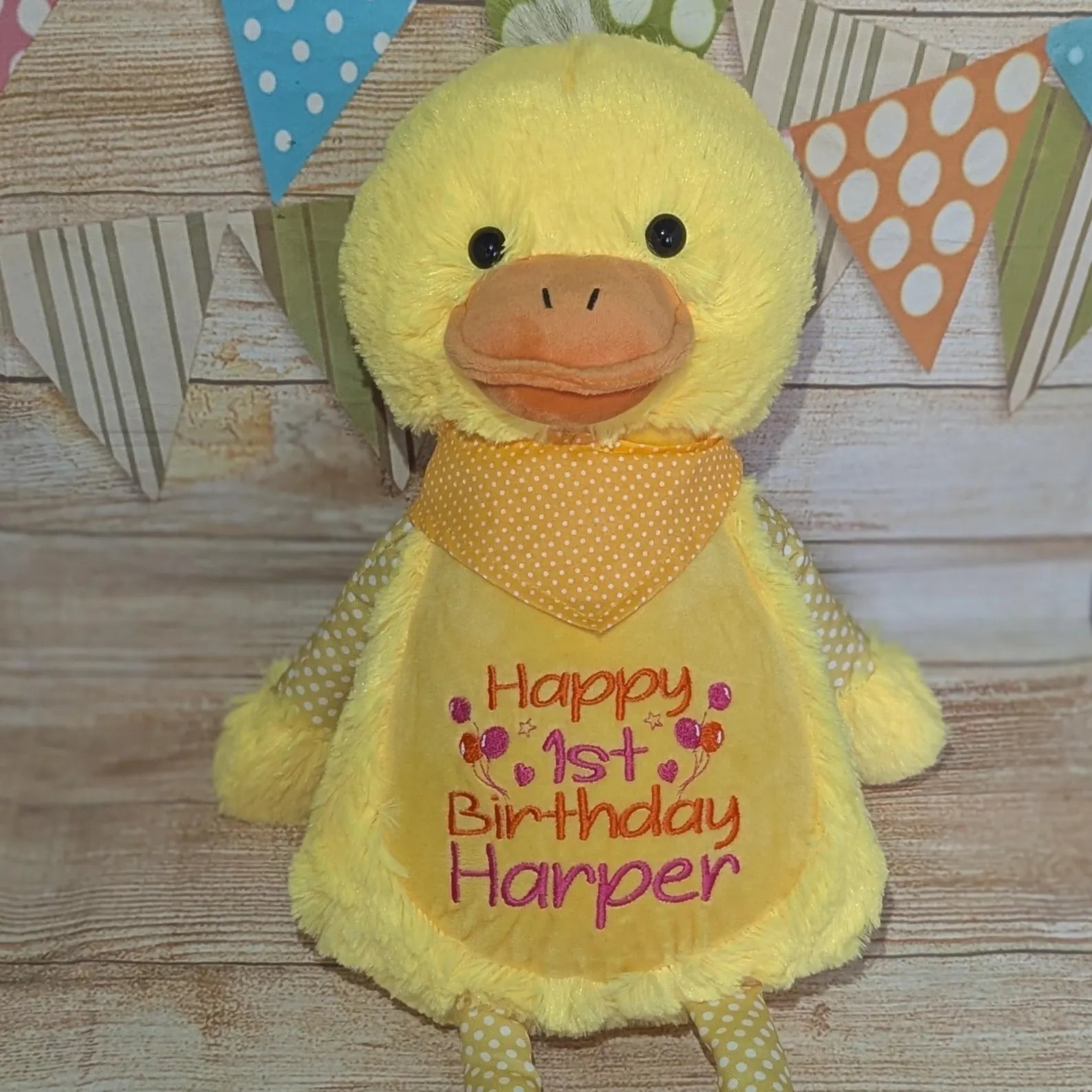 Yellow plush duck with 'Happy 1st Birthday Harper' on a wooden background