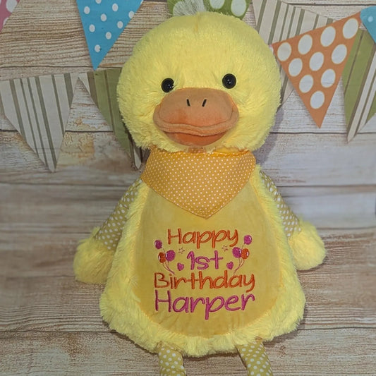 Yellow plush duck with 'Happy 1st Birthday Harper' on a wooden background