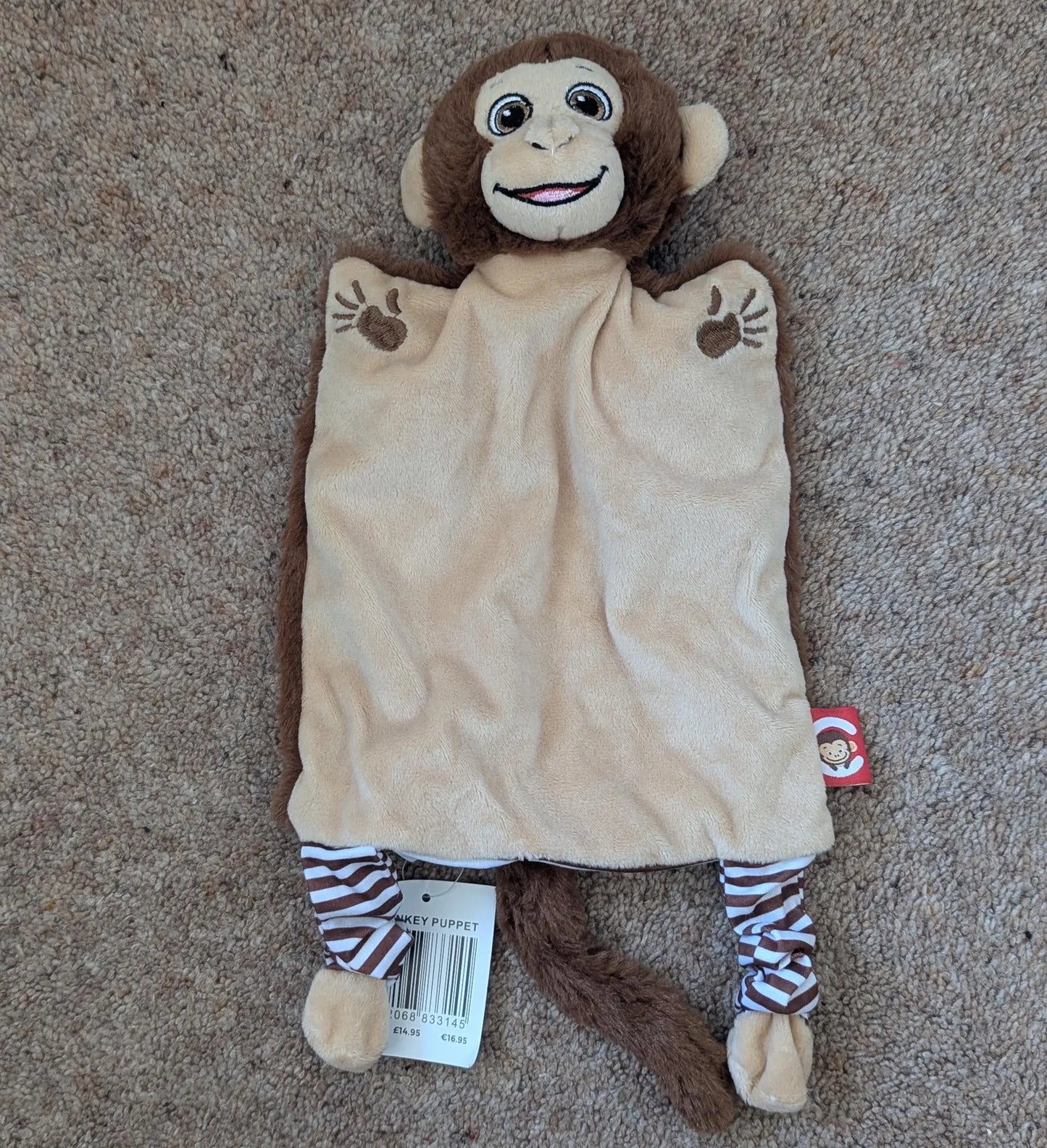 Stuffed monkey toy with a beige blanket on a carpeted floor