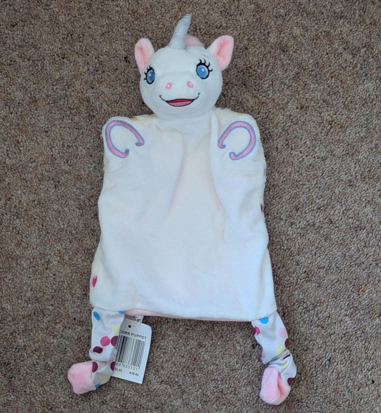 Plush toy with unicorn design on a beige carpet