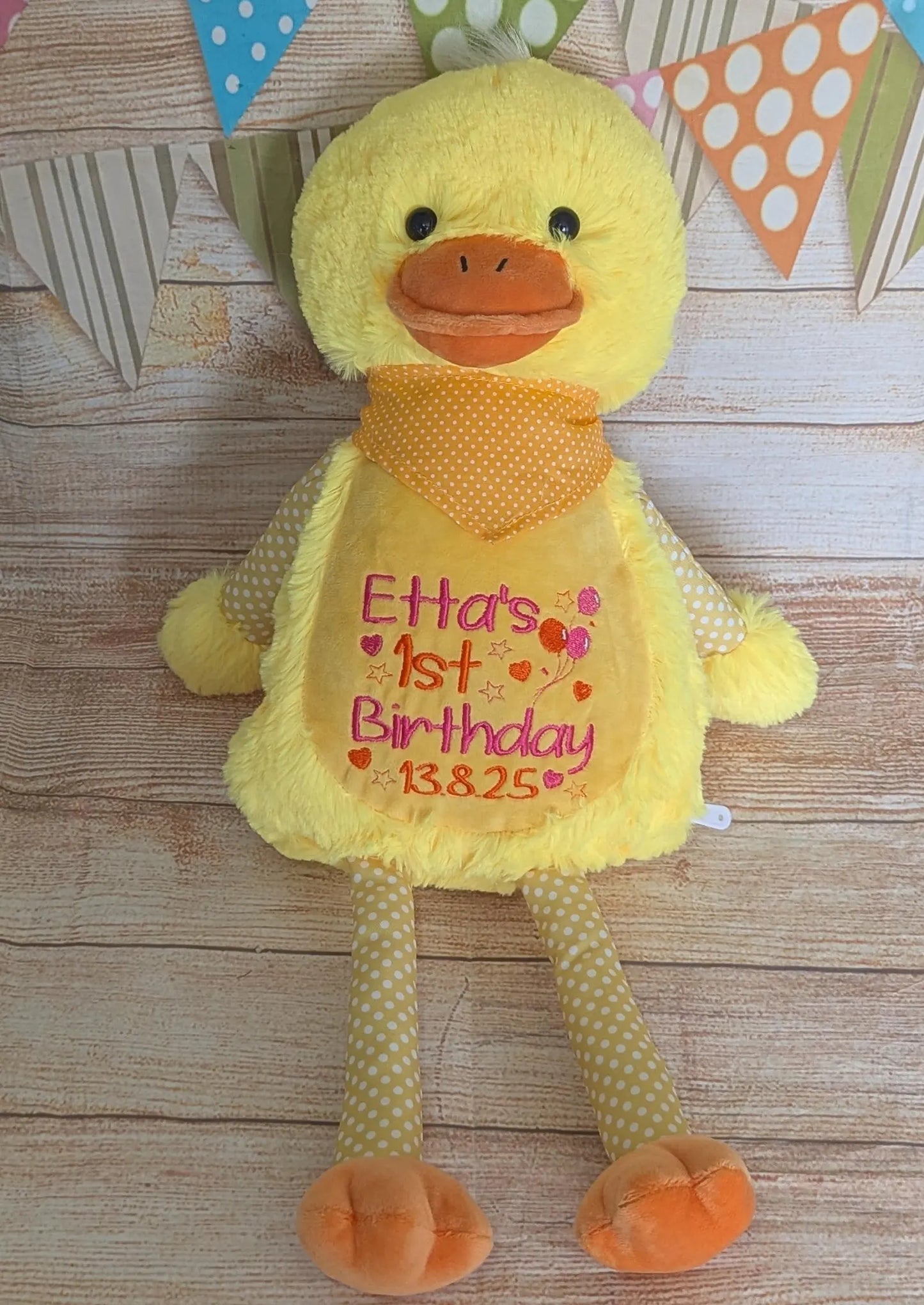 Yellow duck plush toy with personalized text on a wooden surface