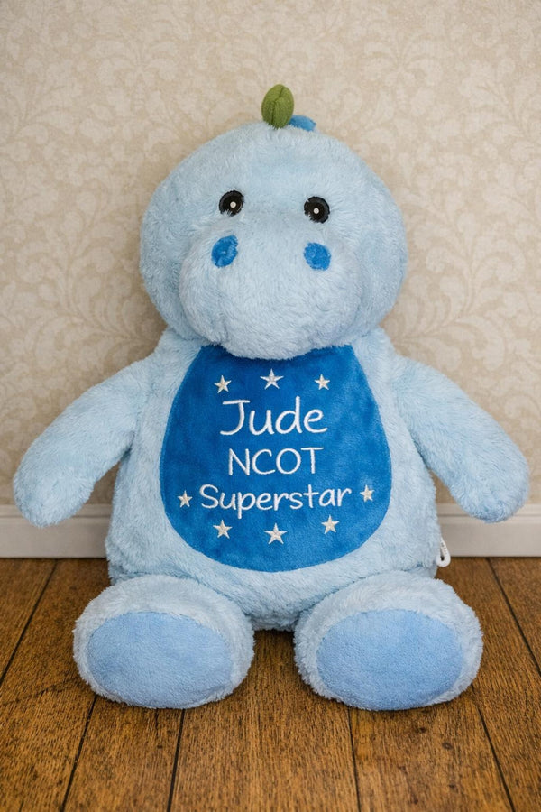 Blue plush toy with 'Jude NCOT Superstar' text on a wooden floor.