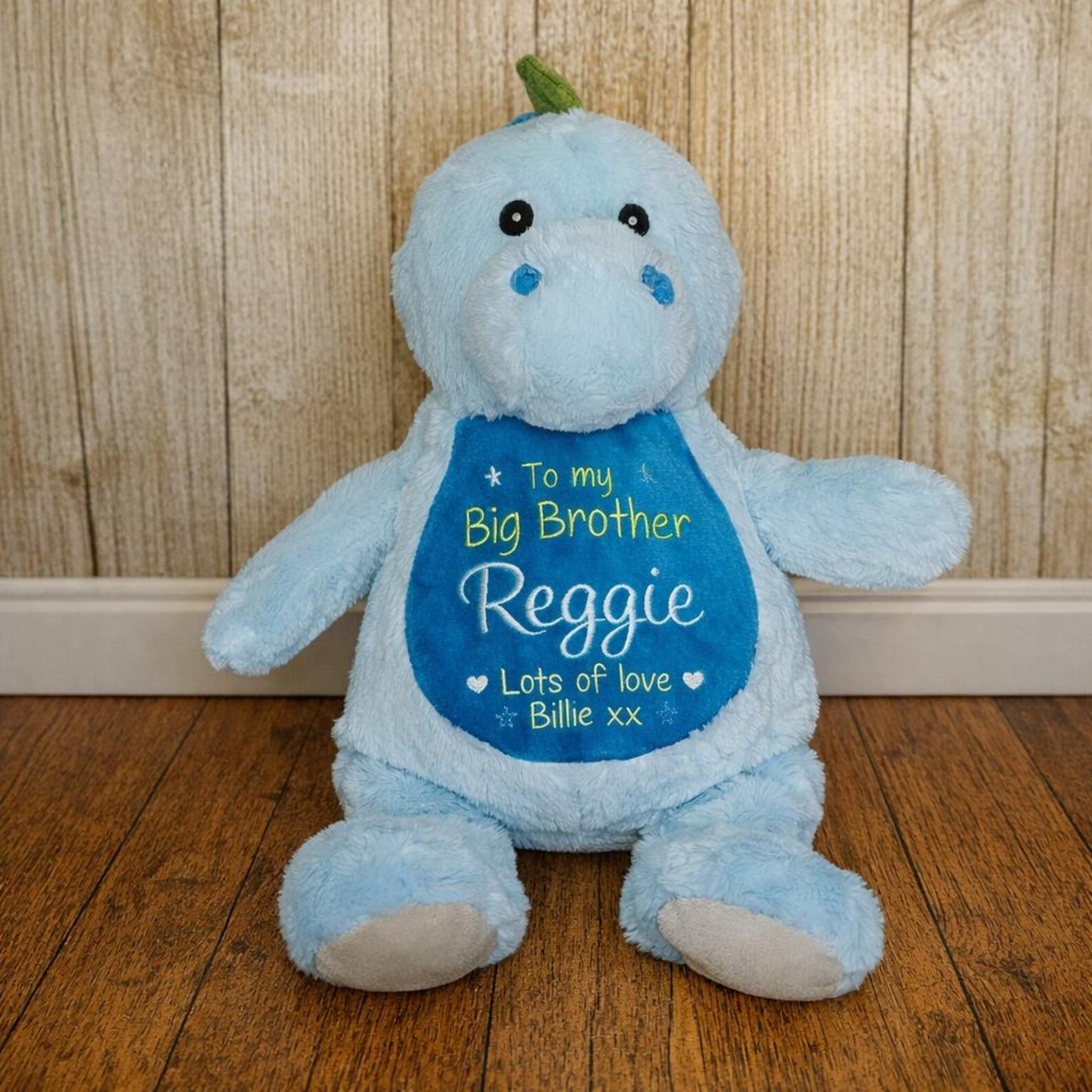 Blue teddy bear with a personalized message on a wooden floor and wall background