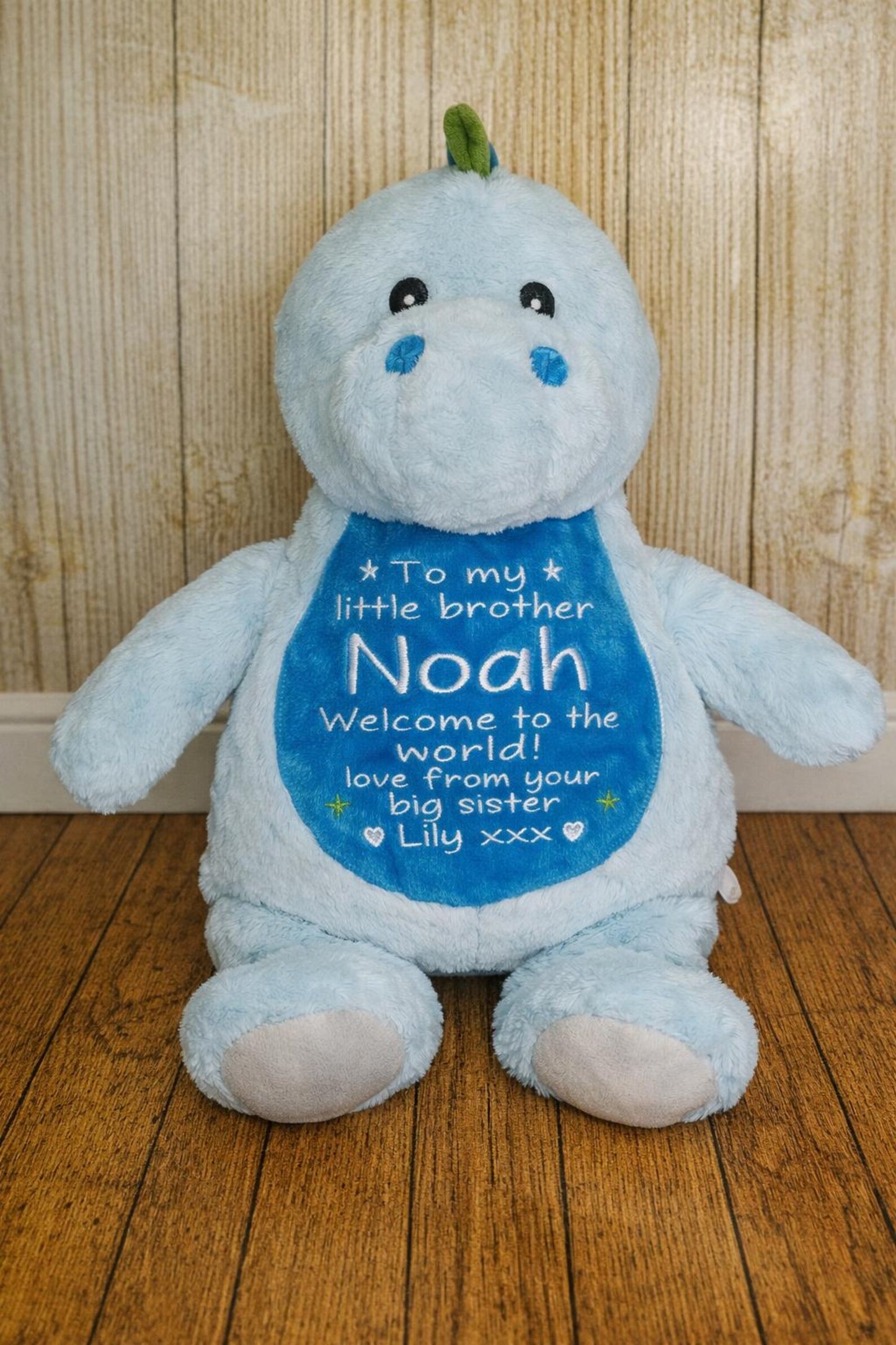 Blue plush toy with a personalized message on a wooden floor.