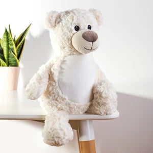 White teddy bear on a white stool with a plant in the background